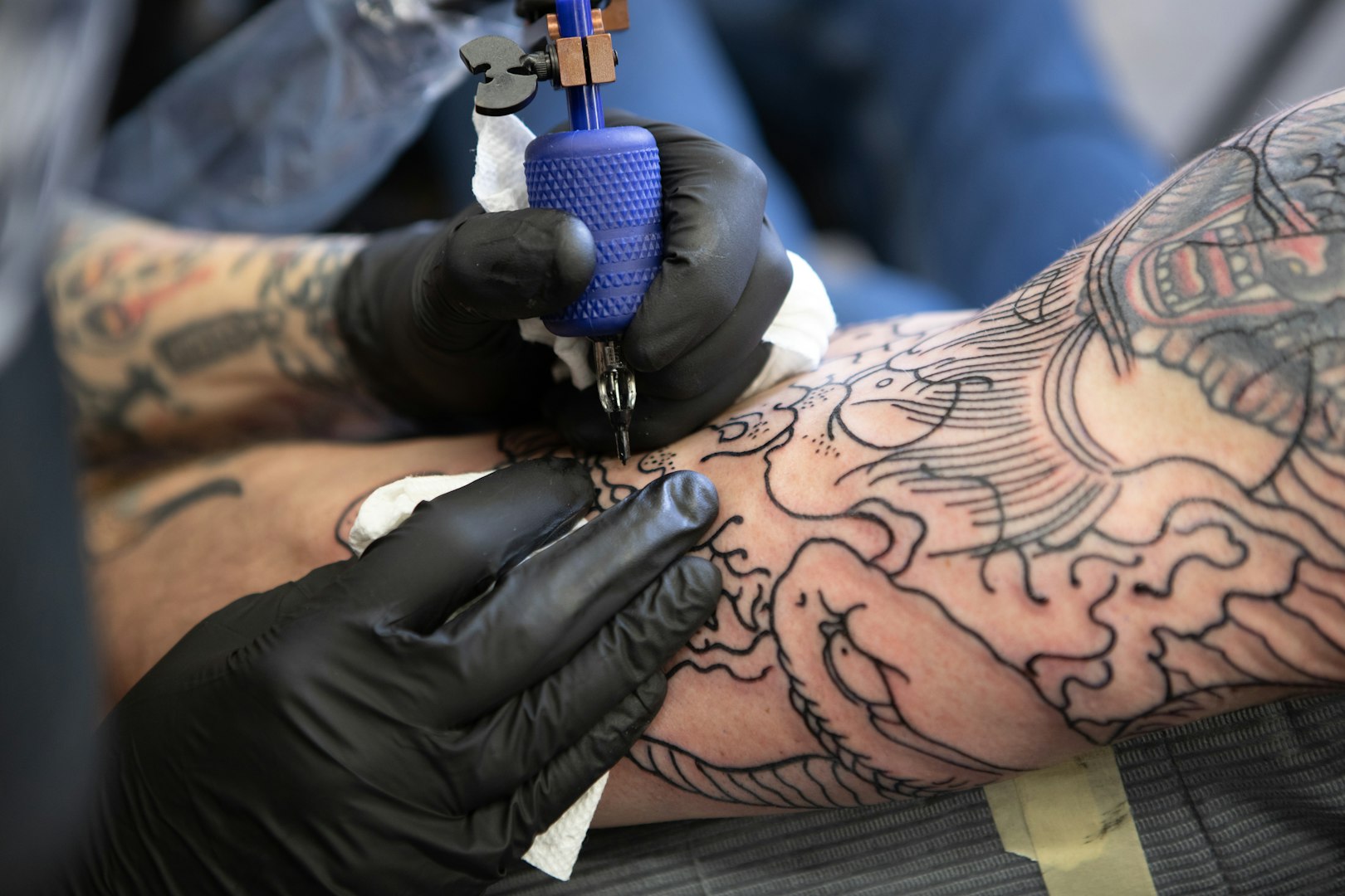 shallow focus photo of person tattooing person's right arm